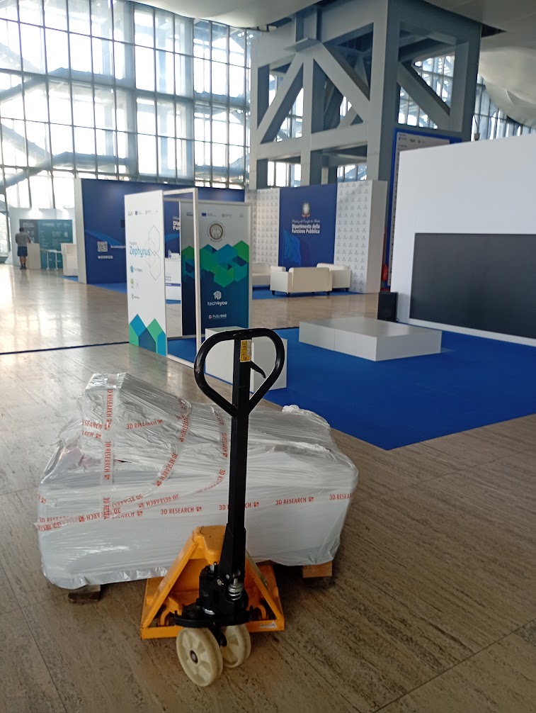 Collo imballato su transpallet nel padiglione della Nuvola di Roma con lo stand Tech4You sullo sfondo